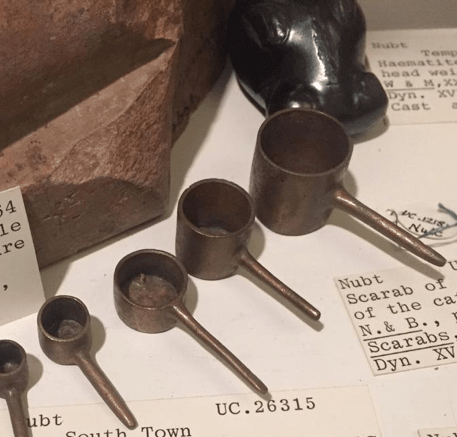 Misurini in bronzo per la polvere d'oro e peso in ematite in forma di ippopotamo esposti al Petrie Museum