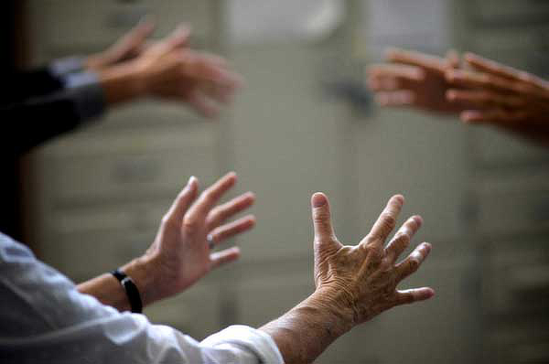 Mani di tre persone anziane che stanno praticando il Qigong in cerchio